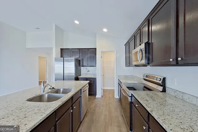a kitchen with granite countertop stainless steel appliances a sink stove and refrigerator