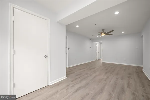 an empty room with wooden floor fan and windows