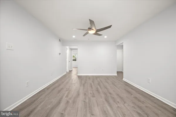 an empty room with wooden floor and ceiling fan
