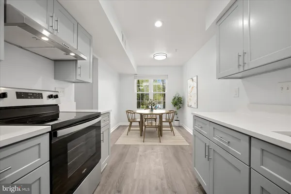 a kitchen with granite countertop a stove chairs and wooden floor