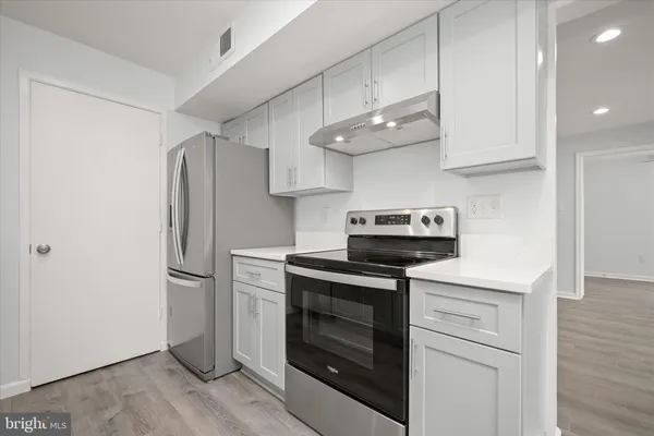 a kitchen with stainless steel appliances white cabinets and a wooden floor