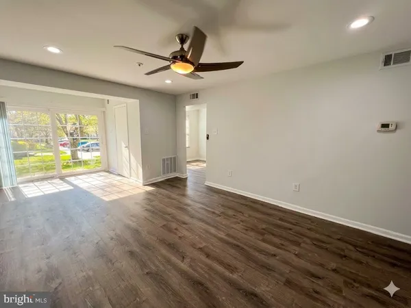 an empty room with wooden floor and windows