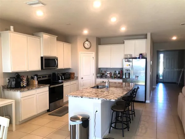 a kitchen with a sink chairs and refrigerator