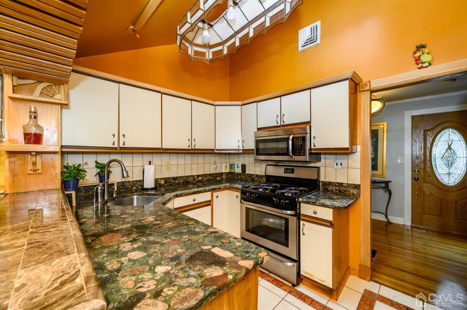10 Stiles Road Warren, NJ 07059 - Photo 15 of 39 a kitchen with stainless steel appliances granite countertop a stove top oven a sink a dining table and chairs with wooden floor