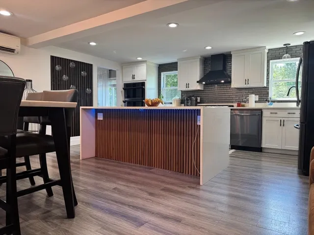 a kitchen with stainless steel appliances granite countertop a table chairs sink and cabinets