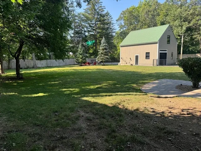 a view of a white house in a big yard with a large trees
