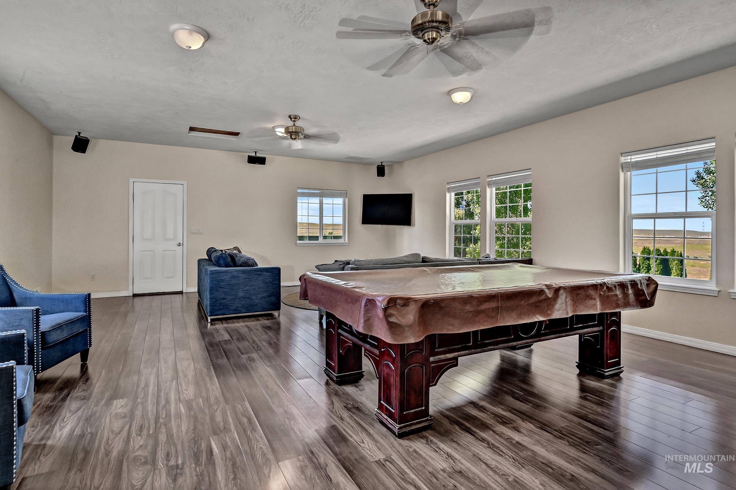 7213 East Columbia Road Boise, ID 83716 - Photo 23 of 47 Spacious recreation room featuring wood-finish flooring, multiple windows providing natural illumination, and ceiling fans for air circulation