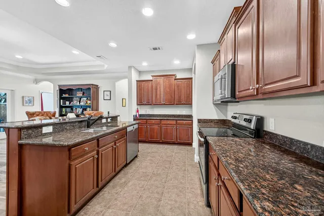 a kitchen with stainless steel appliances granite countertop a stove top oven a sink dishwasher a refrigerator and a fireplace