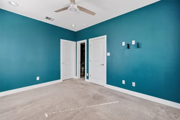 an empty room with closet and a ceiling fan