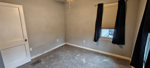 a view of an empty room with window and stairs