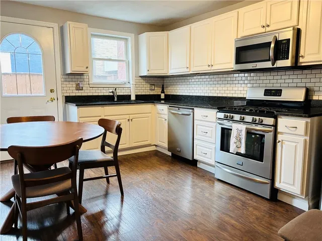 a kitchen with stainless steel appliances a stove a sink and white cabinets