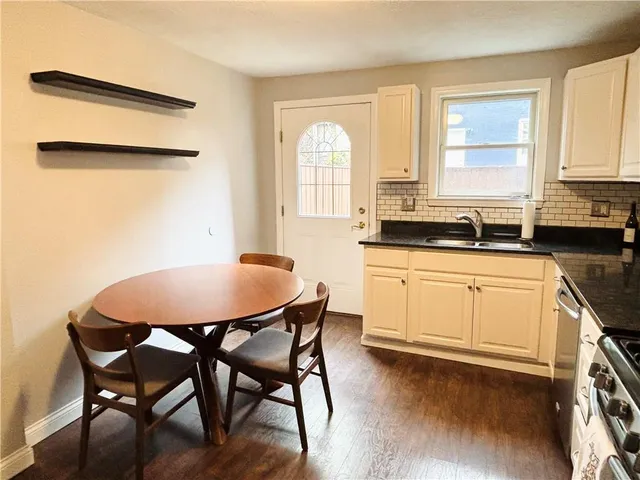 a kitchen with stainless steel appliances granite countertop a stove a sink a dining table and chairs with wooden floor