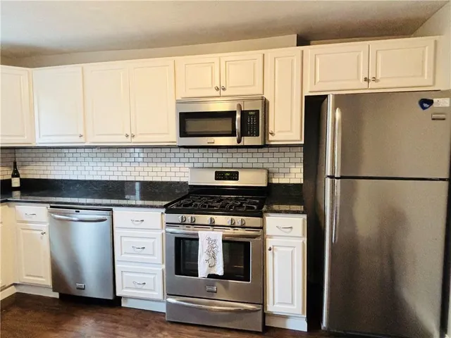 a kitchen with cabinets stainless steel appliances and wooden floor