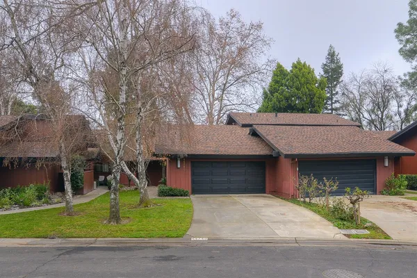 a front view of a house with a garden and trees