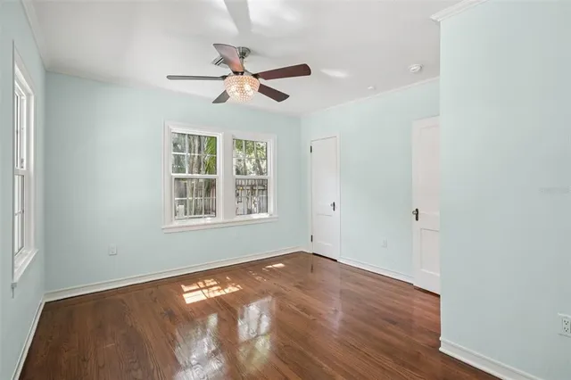 a view of empty room with wooden floor and fan