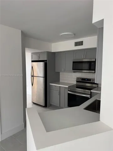 a kitchen with a refrigerator and a stove top oven