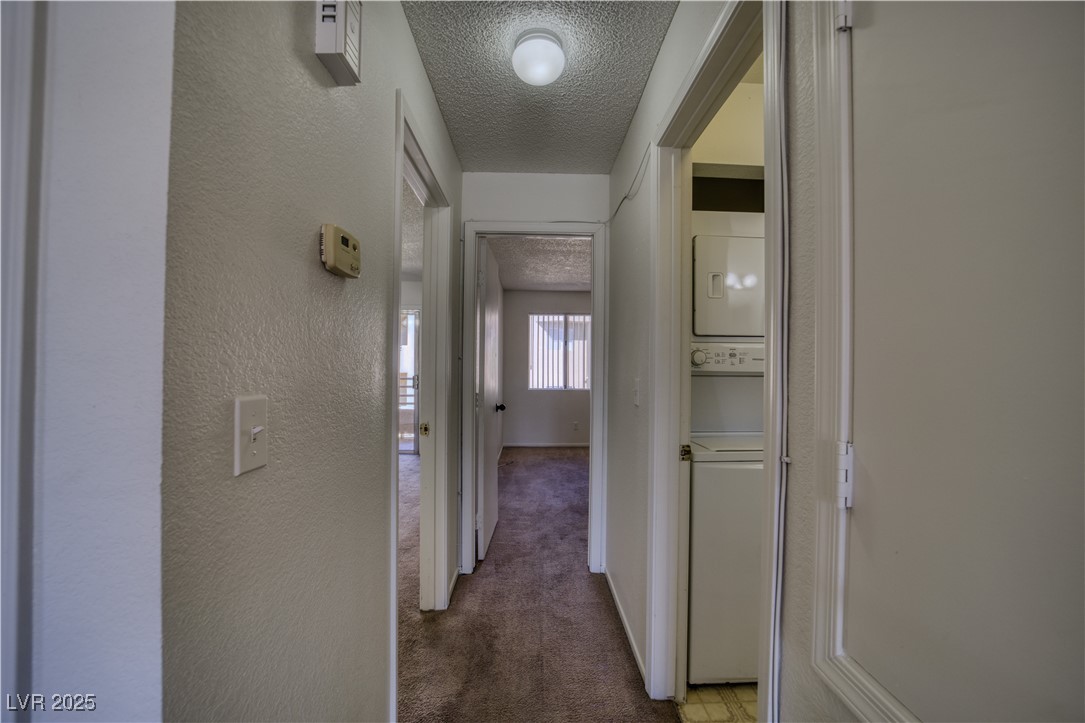 2232 Aspen Mirror Way, Unit 202 Laughlin, NV 89029 - Photo 14 of 39 Corridor featuring a textured ceiling, carpet floors, a textured wall, and stacked washer / drying machine