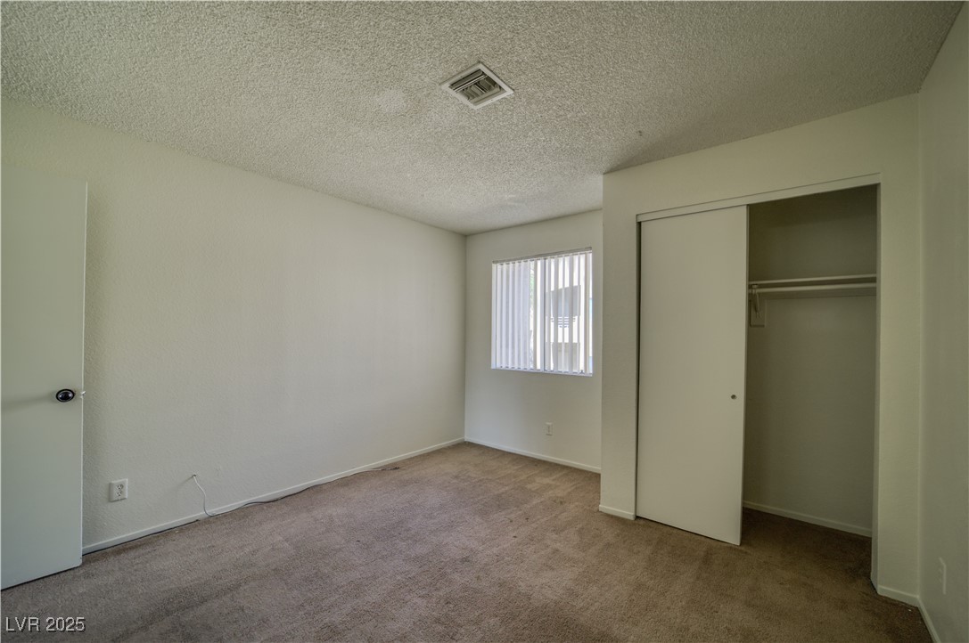 2232 Aspen Mirror Way, Unit 202 Laughlin, NV 89029 - Photo 19 of 39 Unfurnished bedroom featuring carpet flooring, a textured ceiling, and a closet