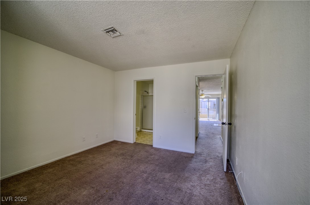 2232 Aspen Mirror Way, Unit 202 Laughlin, NV 89029 - Photo 20 of 39 Unfurnished bedroom featuring a textured ceiling, dark colored carpet, and connected bathroom