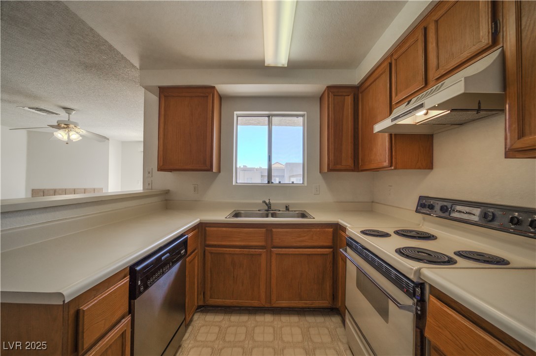 2232 Aspen Mirror Way, Unit 202 Laughlin, NV 89029 - Photo 8 of 39 Kitchen featuring electric stove, brown cabinetry, under cabinet range hood, light countertops, and a textured ceiling