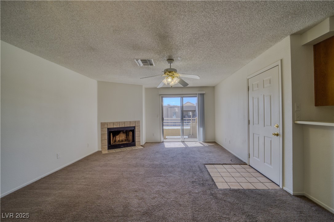 2232 Aspen Mirror Way, Unit 202 Laughlin, NV 89029 - Photo 10 of 39 Unfurnished living room with carpet, a fireplace, a textured ceiling, and a ceiling fan