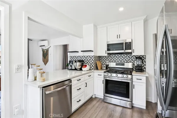 a kitchen with white cabinets stainless steel appliances and wooden floor