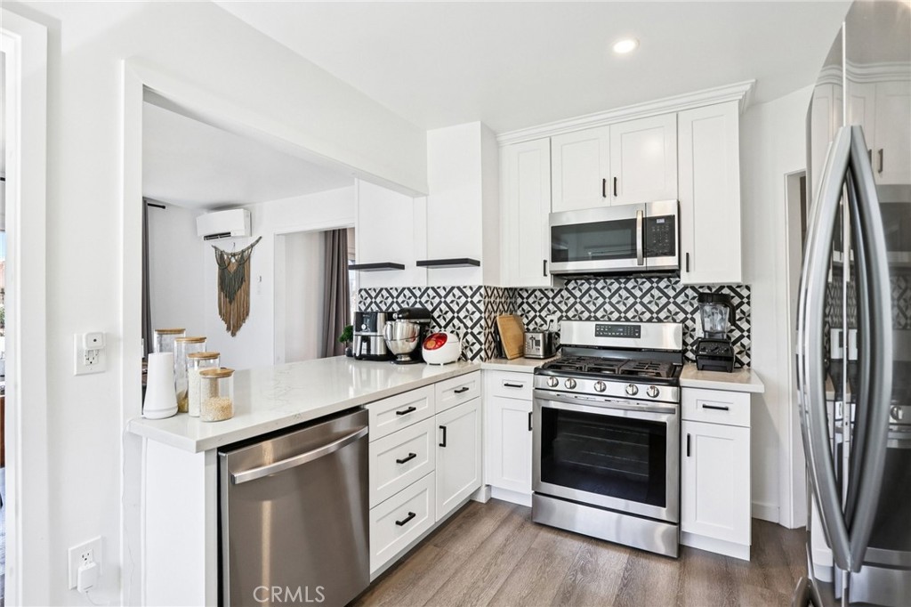 1448 Lemon Avenue Long Beach, CA 90813 - Photo 11 of 19 a kitchen with white cabinets stainless steel appliances and wooden floor