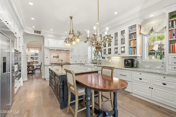a kitchen with stainless steel appliances kitchen island granite countertop a table chairs stove and refrigerator