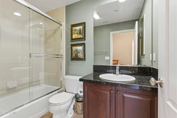 a bathroom with a granite countertop sink toilet a mirror and shower