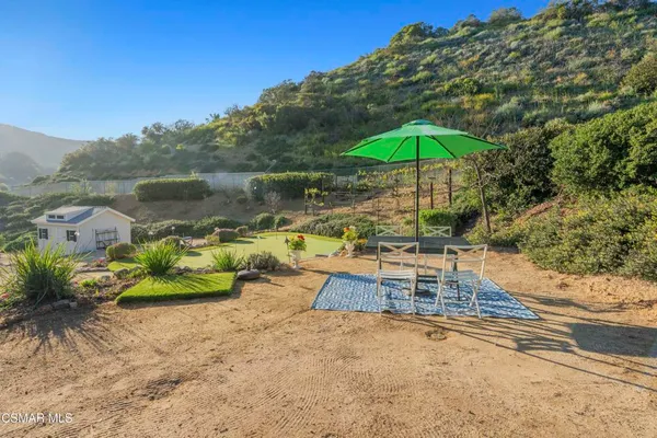 a view of a lake with a table and chairs under an umbrella