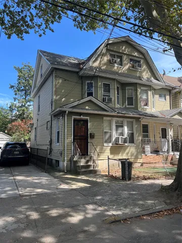 a view of a big house with many windows and a car parked beside it