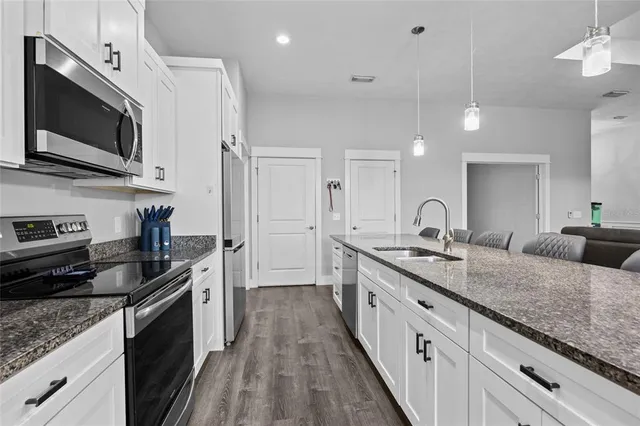 a large kitchen with granite countertop a large counter top appliances and cabinets