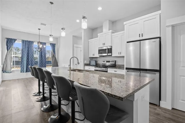 a kitchen with granite countertop a table chairs microwave and refrigerator