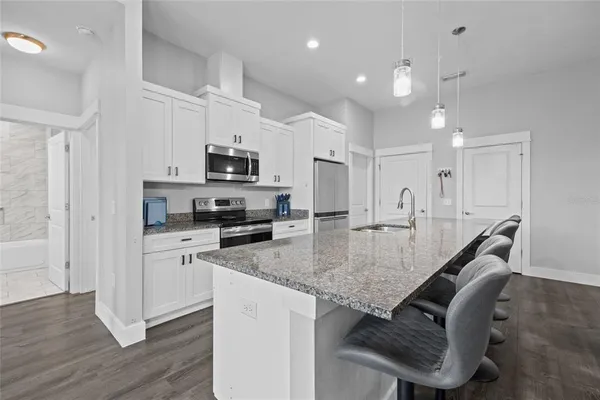 a kitchen with granite countertop a stove a sink a counter space and cabinets