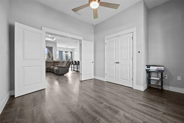 an empty room with wooden floor fan and windows