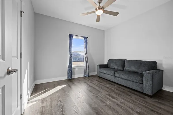 an empty room with wooden floor fan and windows