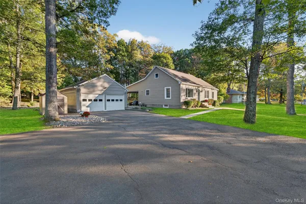a view of a house with a big yard and large trees
