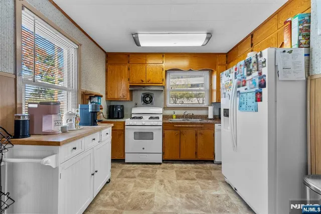 a kitchen with granite countertop appliances a sink and a large window