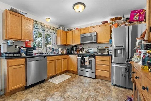 a kitchen with granite countertop a refrigerator stove top oven and sink