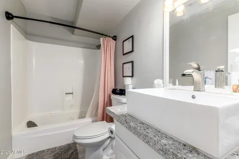 a bathroom with a bathtub shower sink mirror and toilet