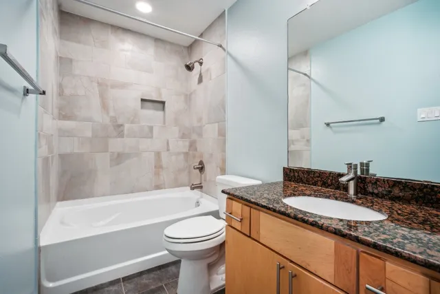 a bathroom with a granite countertop sink toilet mirror and bathtub