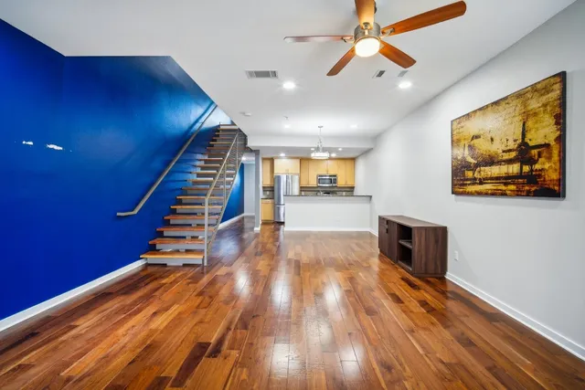 a view of a living room with wooden floor and a ceiling fan