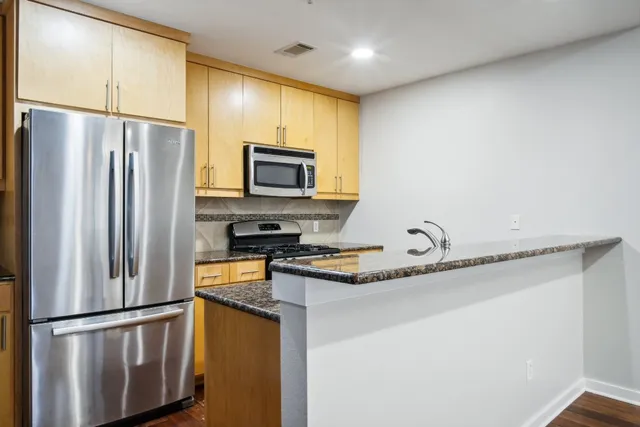 a kitchen with stainless steel appliances granite countertop a refrigerator a stove a sink and a microwave