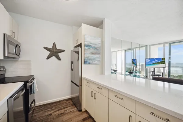 a hall with kitchen island white cabinets and wooden floor