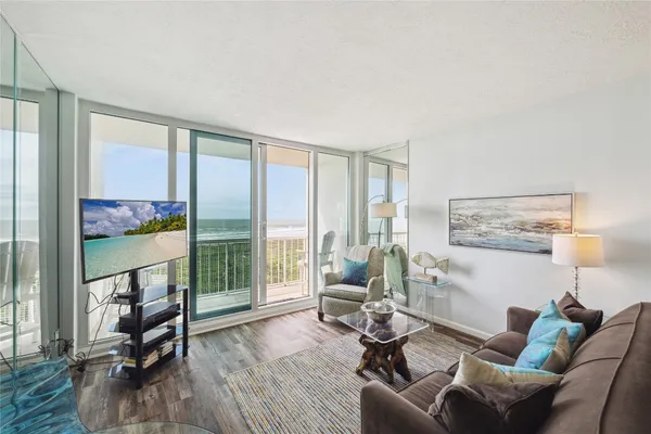 a living room with furniture a floor to ceiling window and wooden floor