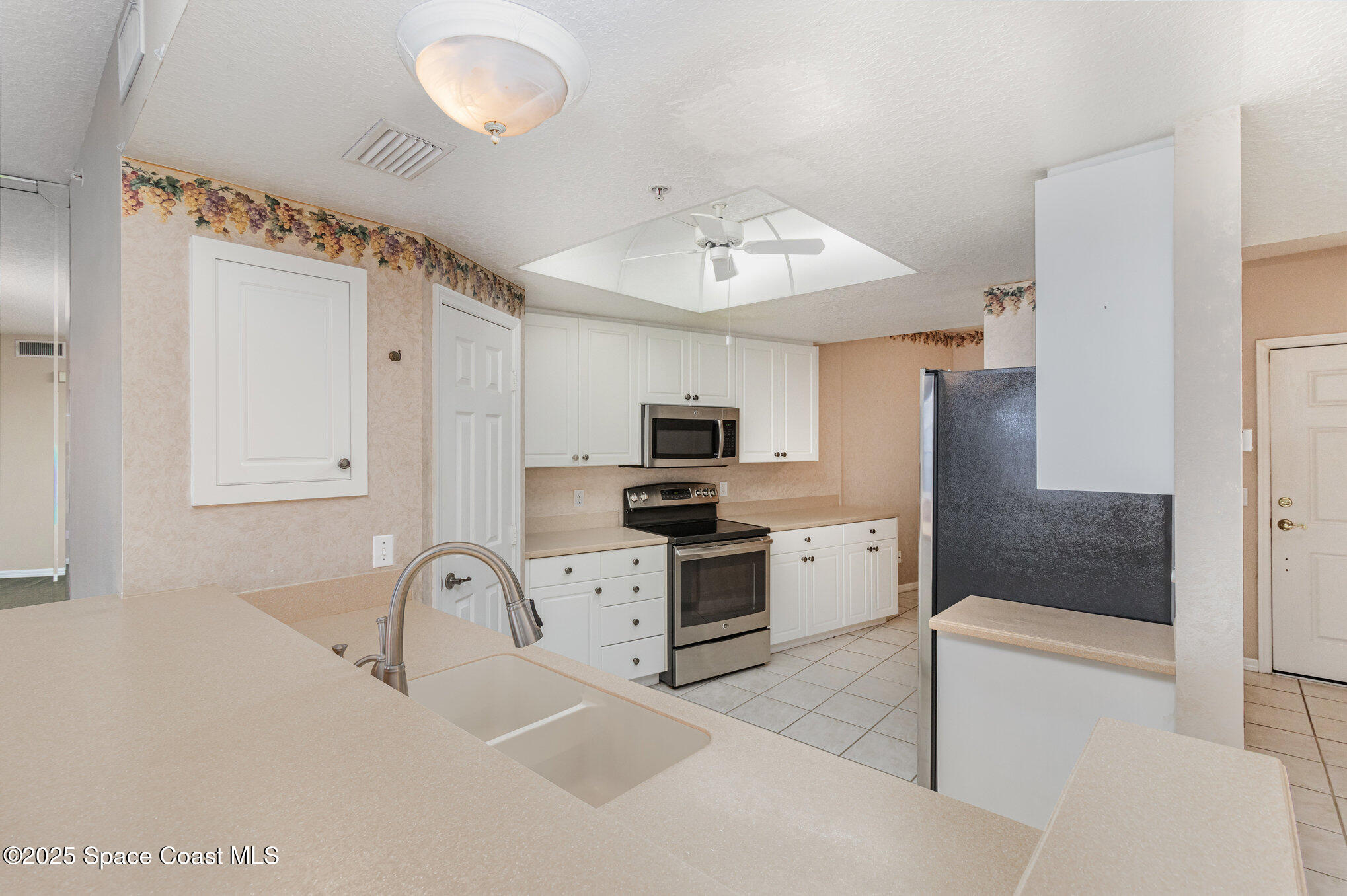 104 Riverside Drive, Unit 403 Cocoa, FL 32922 - Photo 7 of 20 a kitchen with white cabinets and stainless steel appliances