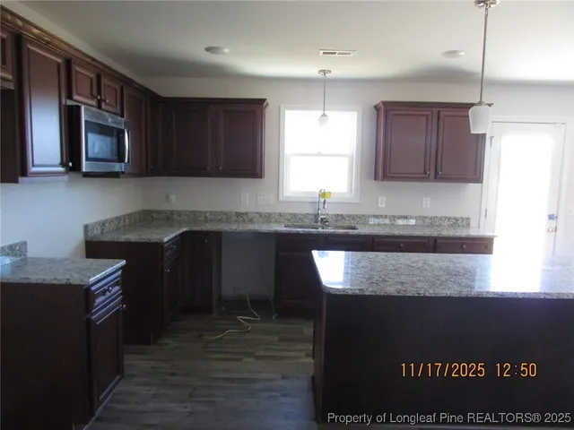 a kitchen with granite countertop a sink cabinets and wooden floor
