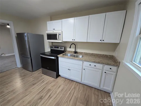 a kitchen with granite countertop white cabinets and stainless steel appliances