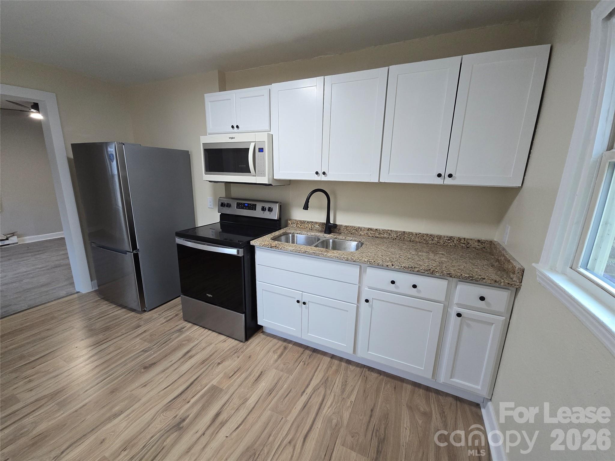 a kitchen with granite countertop white cabinets and stainless steel appliances