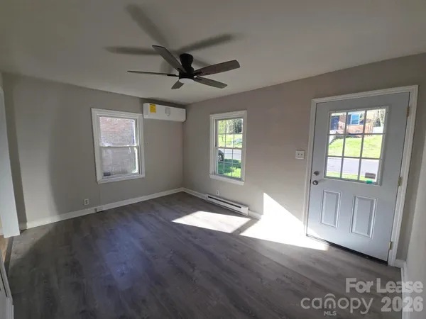 a view of an empty room with a window and wooden floor
